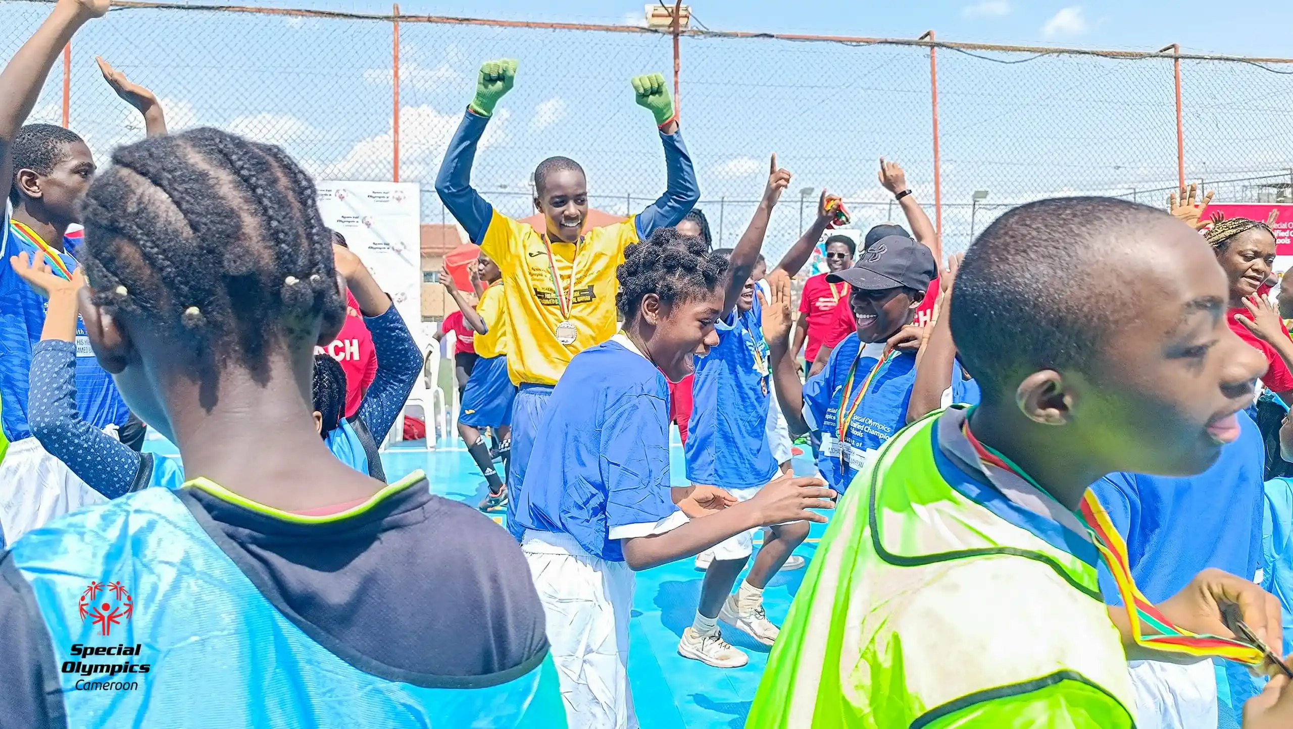 Jeunes athlètes médaillés célébrant la victoire les bras levés sur le terrain