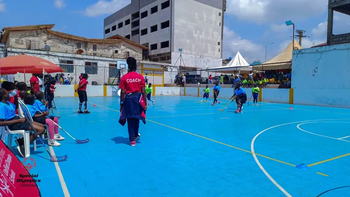 Terrain bleu de floorball en plein match, entraîneur au premier plan