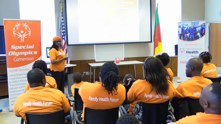 Intervenante devant les familles au Forum de Santé des Familles, près d’une bannière de Special Olympics Cameroun