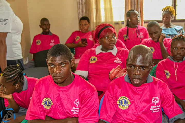 Participants en tee-shirts roses aux couleurs de Special Olympics Cameroun, assis lors d’une rencontre