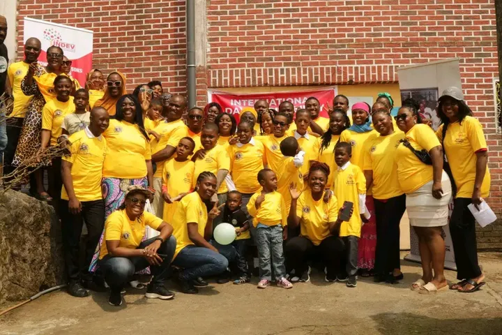 Photo de groupe d’adultes et d’enfants en tee-shirts jaunes devant un bâtiment en briques