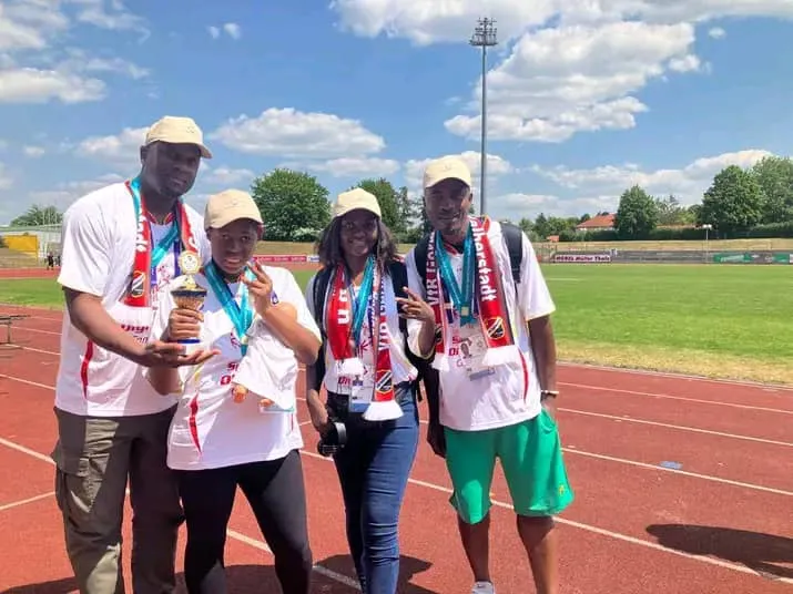 Délégation camerounaise posant avec médailles et trophée sur une piste d’athlétisme