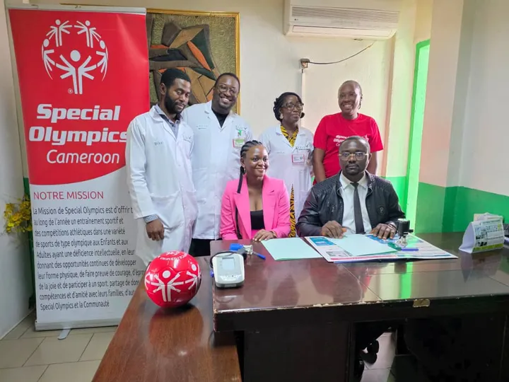 Équipe médicale en blouse blanche et responsables réunis autour d’un bureau près d’une bannière de Special Olympics Cameroun