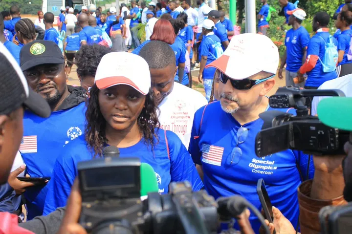 Une femme répond aux médias au milieu de participants en tee-shirts bleus